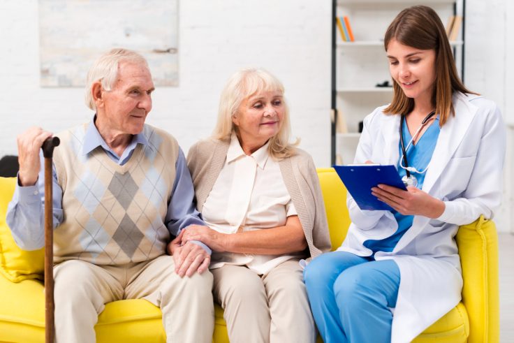 nurse sitting with old man woman sofa