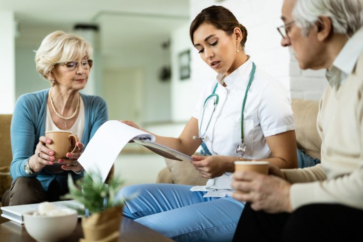 young healthcare worker senior couple analyzing medical test results during home visit